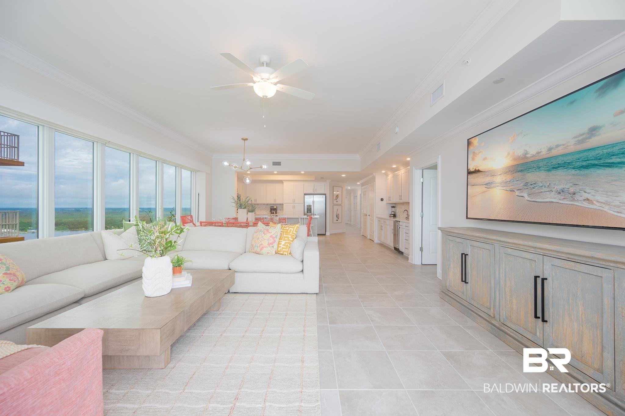 Image 4: Expansive open-concept living area featuring floor-to-ceiling windows, light tile flooring, crown molding, and a contemporary ceiling fan