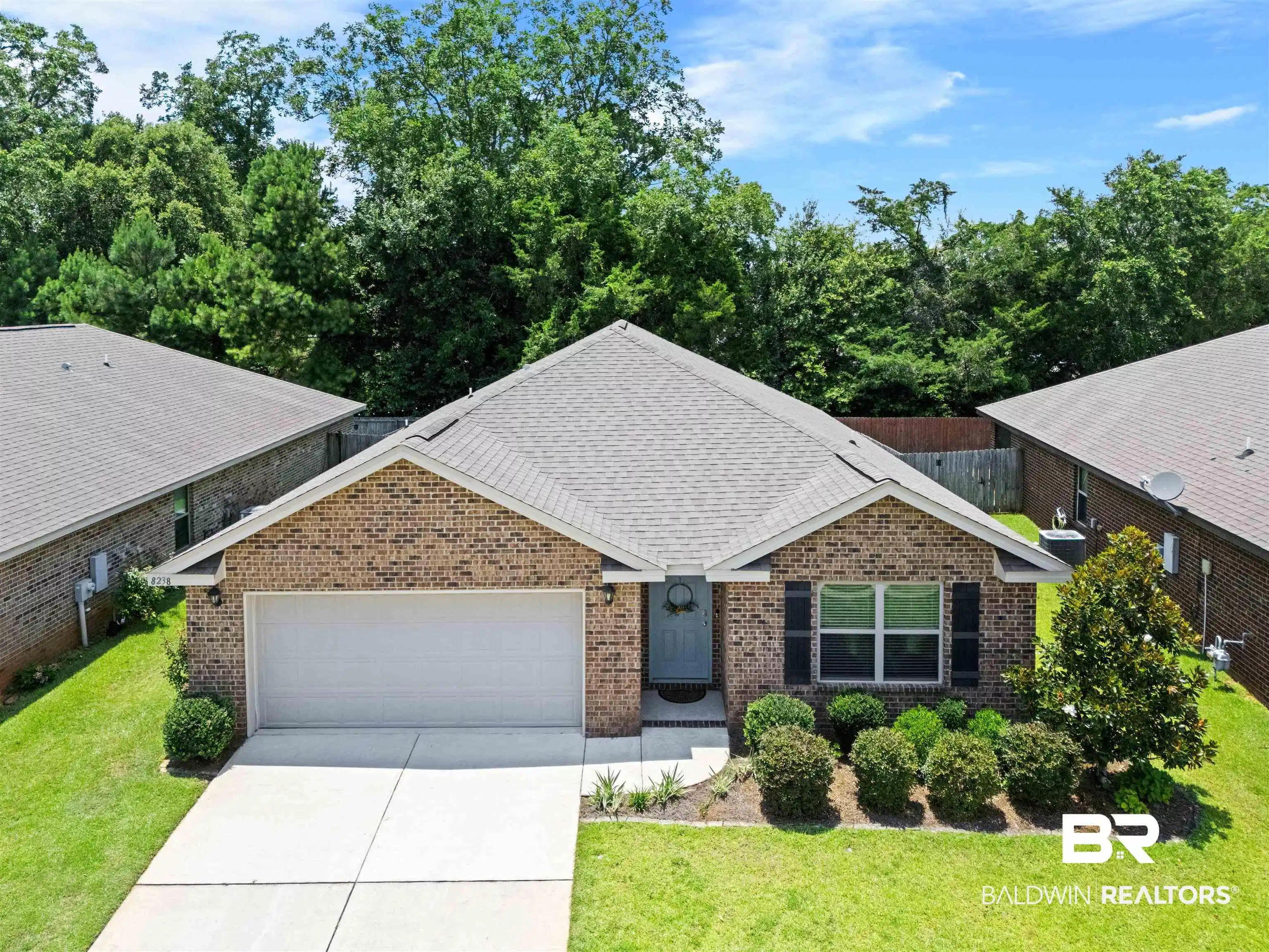 Image 1: Brick exterior home featuring a light gray shingle roof, attached garage with concrete driveway, and established front landscaping