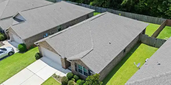 Image 3: Aerial perspective showcasing a single-story brick exterior residence with an attached garage and a concrete driveway