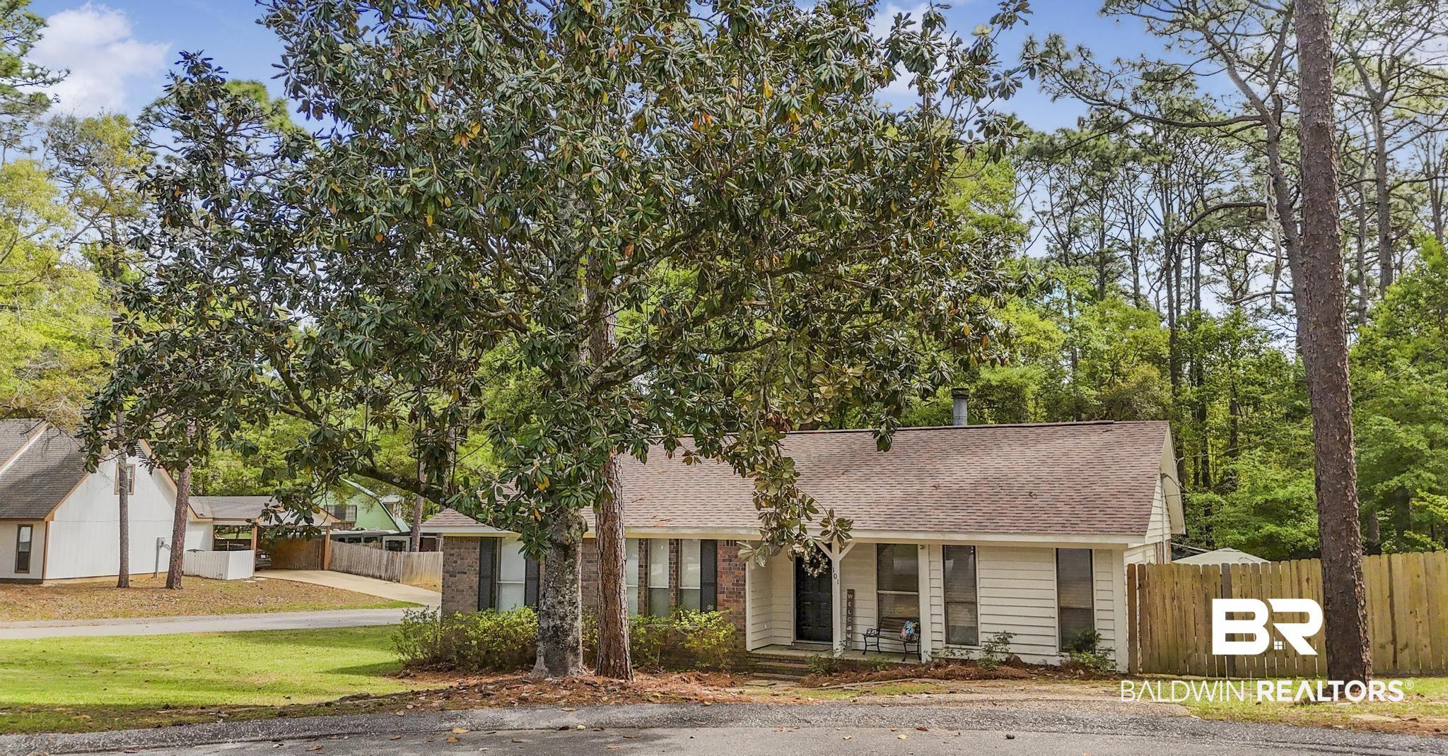 Image 4: Cottage-style residence featuring a prominent front yard tree, a partial brick facade, and white siding