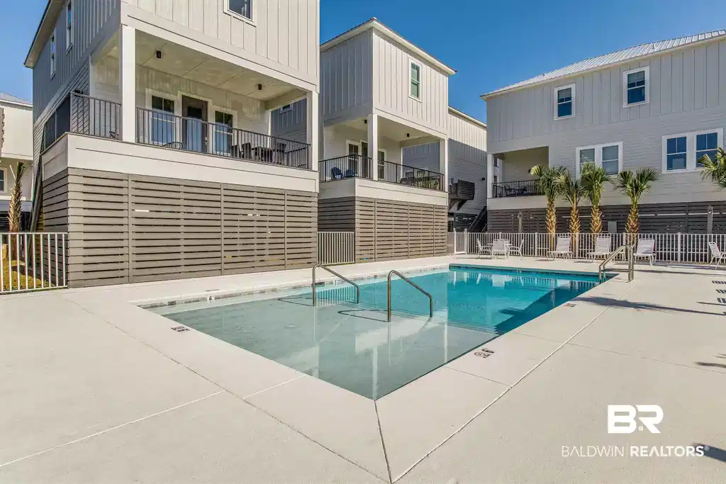 Image 1: Community swimming pool featuring a spacious concrete deck and integrated entry steps