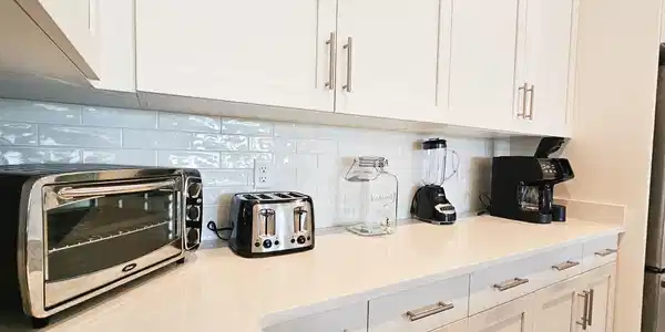 Image 4: Kitchen area featuring light cabinetry with brushed nickel hardware, light-toned countertops, and a subway tile backsplash