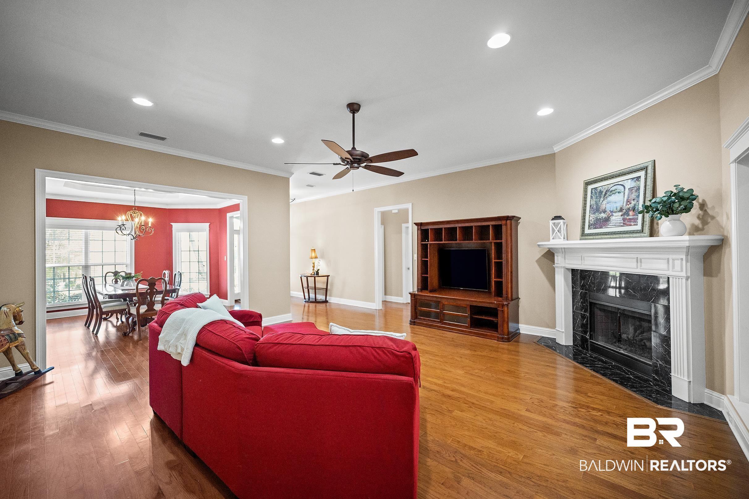 Image 4: Living room featuring wood finished floors, ceiling fan, crown molding, a premium fireplace, and hanging lights