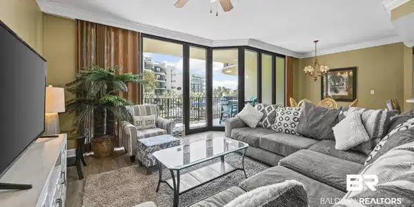 Image 2: Living room featuring expansive windows, ceiling fan, ornamental molding, hanging lights, and dark wood-style flooring