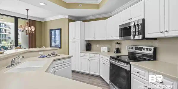 Image 4: Kitchen featuring stainless steel appliances, white cabinetry, light countertops, a chandelier, and a textured ceiling