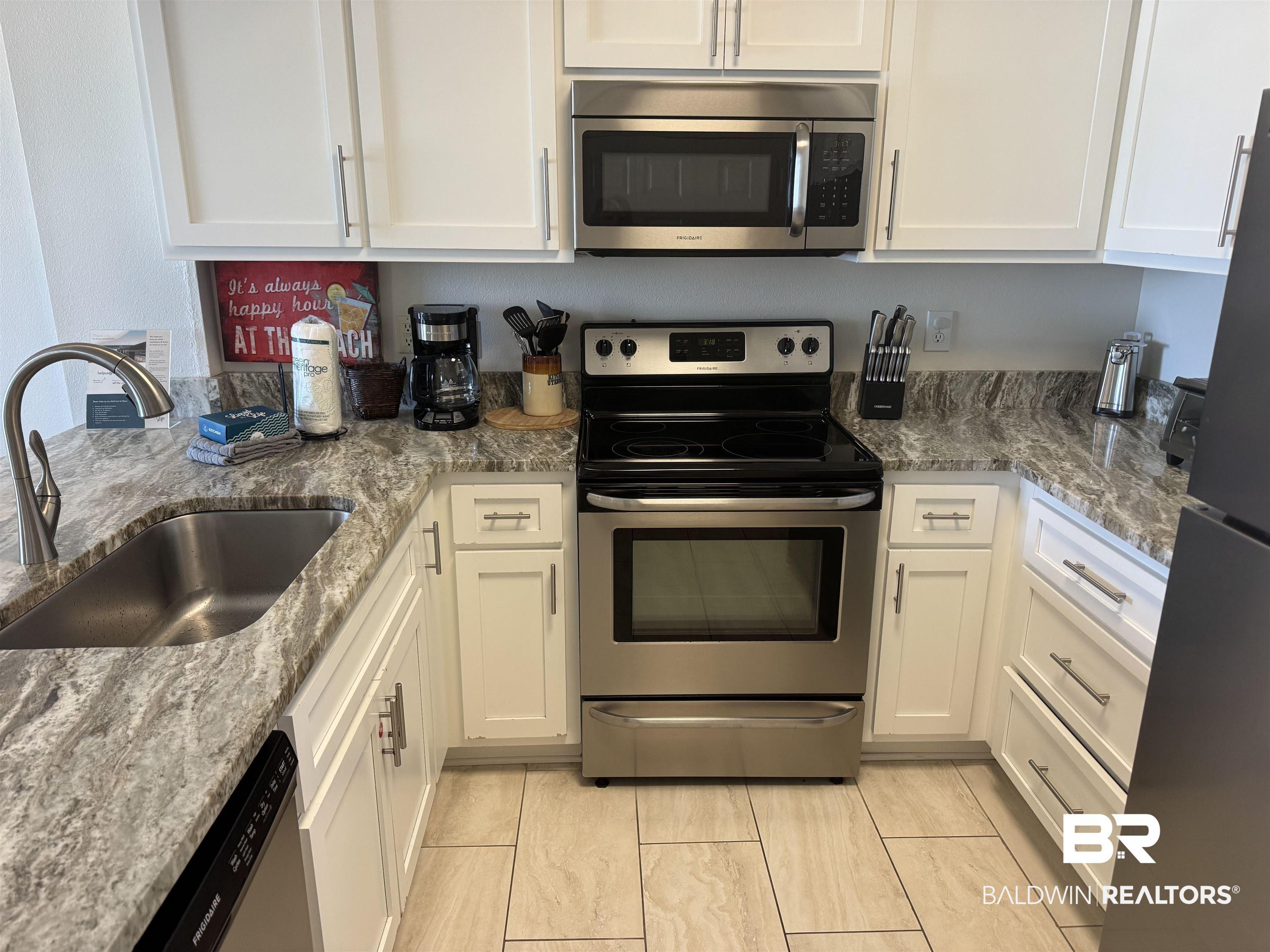 Image 2: Kitchen featuring stainless steel appliances, white Shaker cabinetry, and white/gray stone countertops