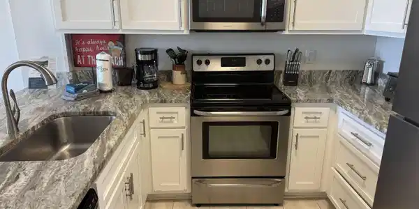 Image 2: Kitchen featuring stainless steel appliances, white Shaker cabinetry, and white/gray stone countertops
