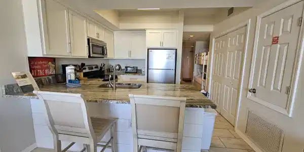 Image 3: Updated kitchen featuring white cabinetry, stainless steel appliances, "Fantasy Brown" counter tops with a large undermount  SS sink, and tile flooring!