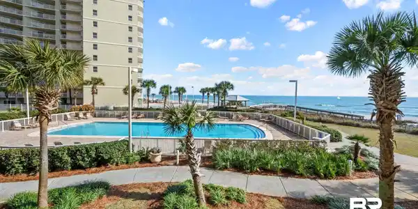 Image 2: Resort-style pool area featuring palm trees, a large swimming pool, and a walkway to the ocean