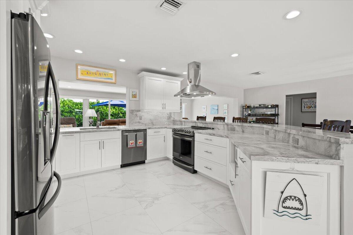 Image 2: Expansive kitchen featuring white cabinetry, light