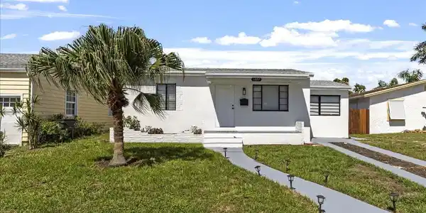 Image 3: White exterior with black-trimmed windows, a palm