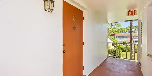Image 3: Entryway featuring a solid orange door with brass