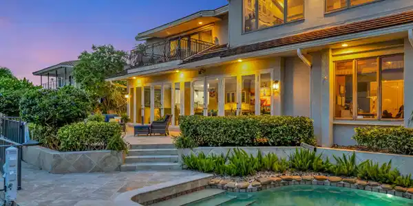 Image 4: The illuminated rear elevation, pool, and waterfro