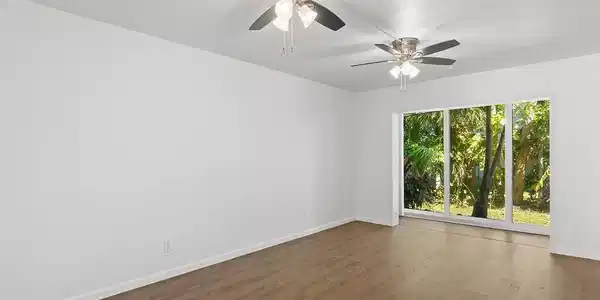 Image 3: Spacious room featuring wood-finish flooring, whit
