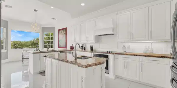Image 4: Bright kitchen featuring white cabinetry, polished