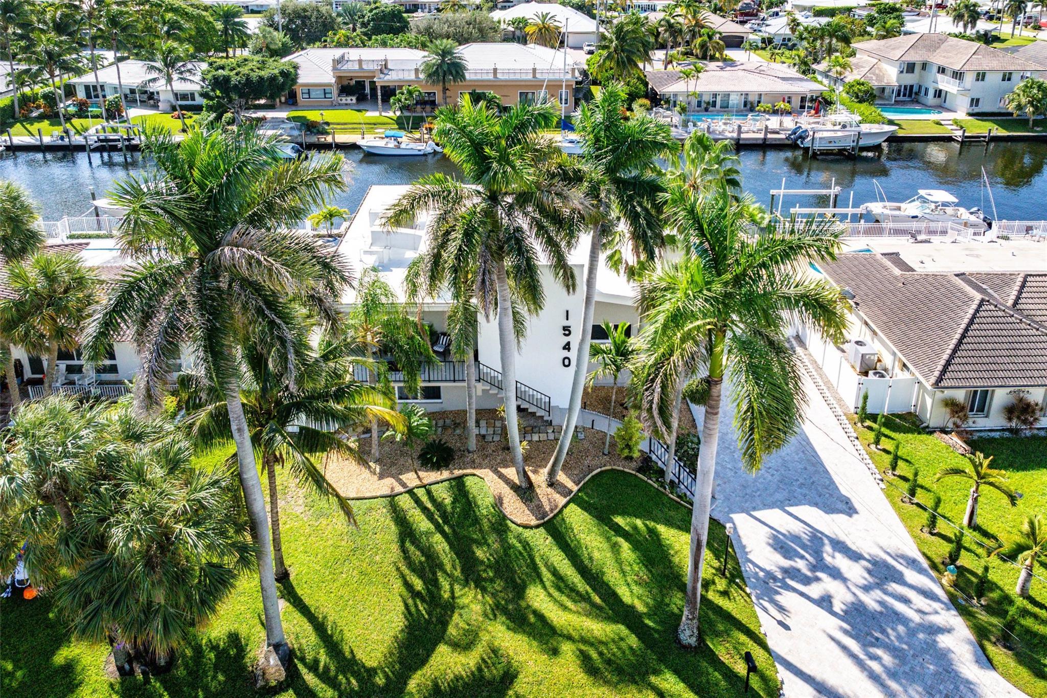 Image 3: Aerial front exterior, driveway + palms