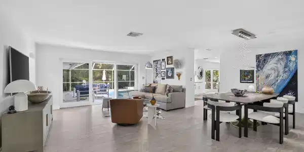 Image 3: Open-concept living space featuring light-toned ti
