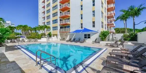 Image 3: Outdoor pool with blue and white tile border, surr