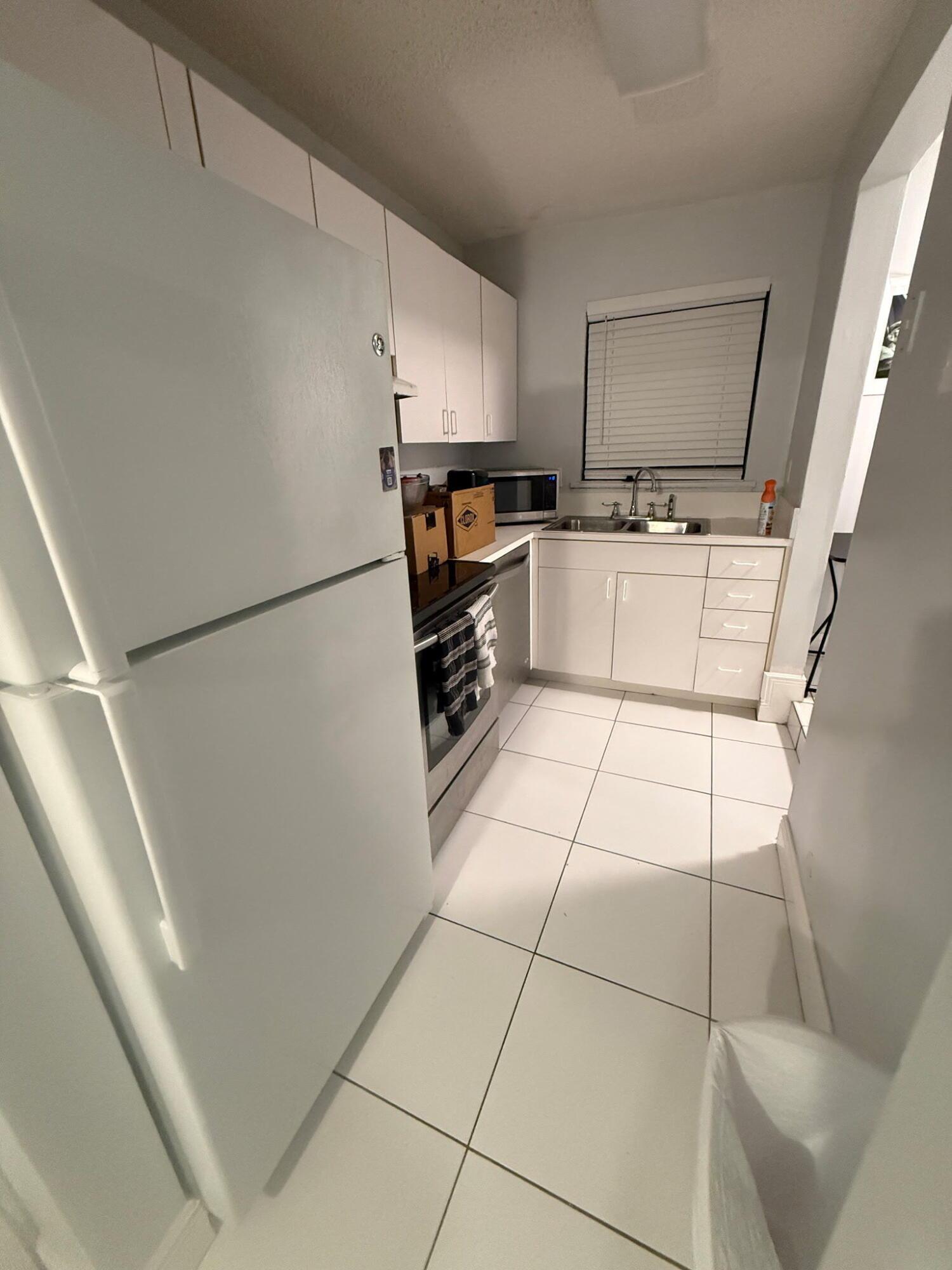Image 4: Compact kitchen featuring white cabinetry, white t