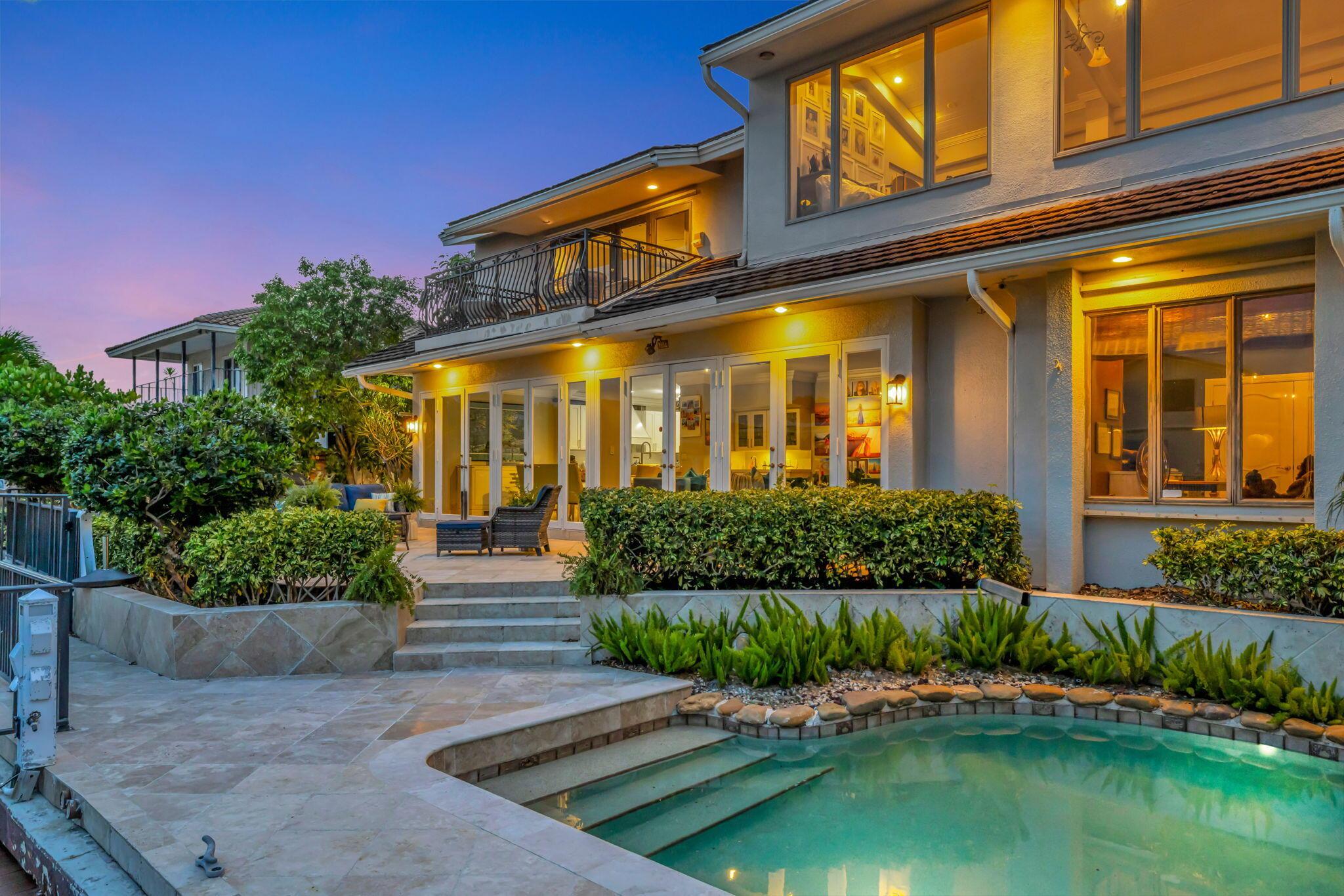 Image 4: The illuminated rear elevation, pool, and waterfro