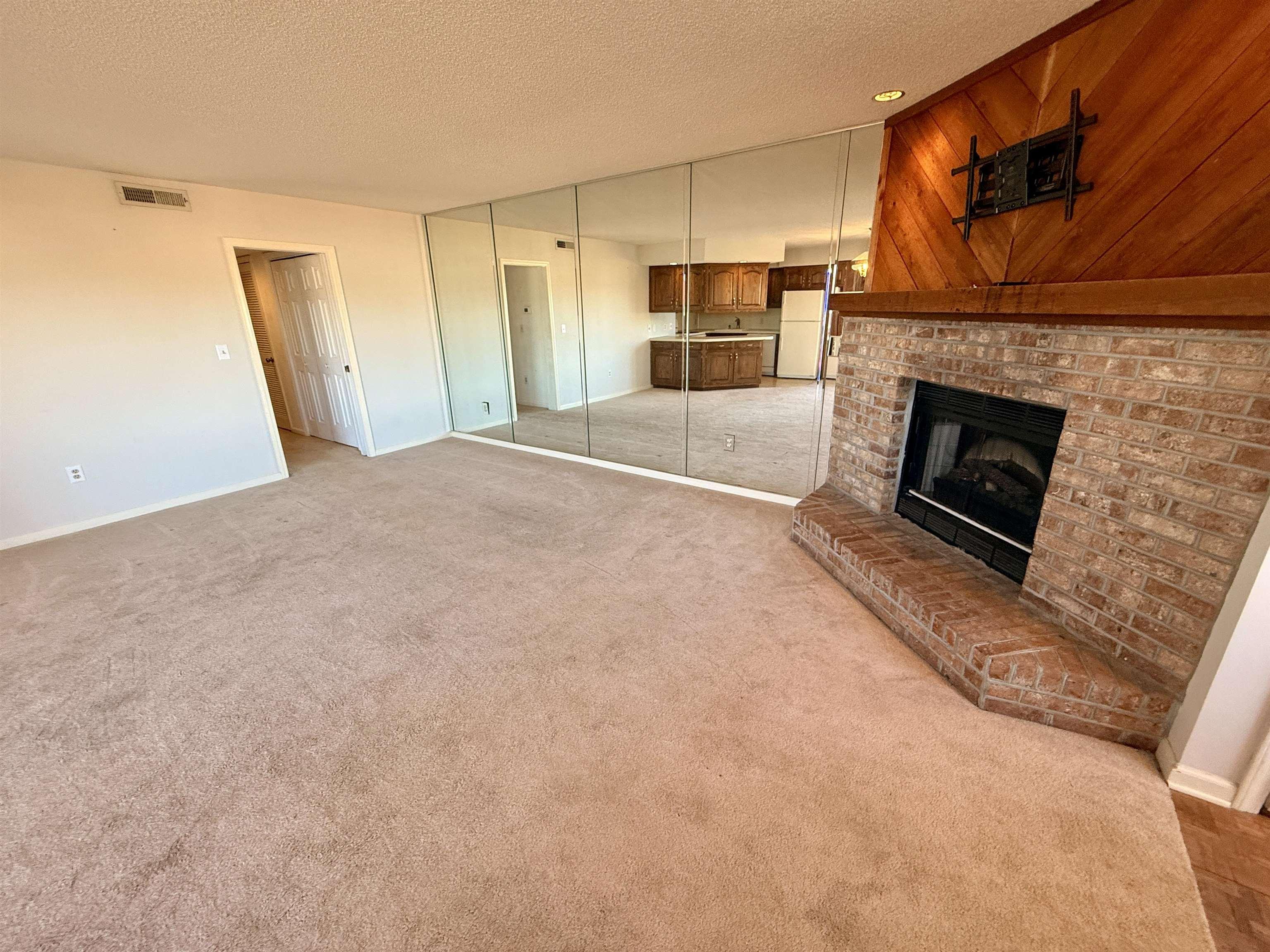 Image 3: Unfurnished living room with light carpet, a brick