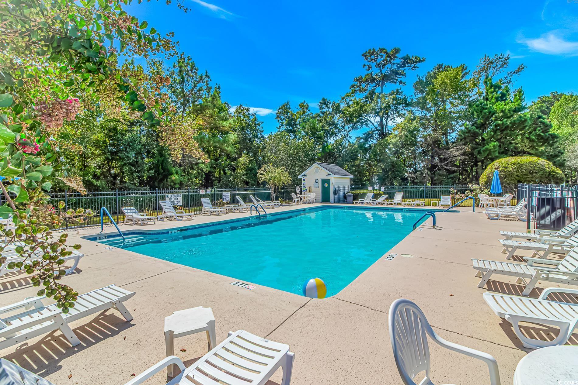 Image 2: Community pool with a patio area and view of woode Image 2: Community pool with a patio area and view of woode