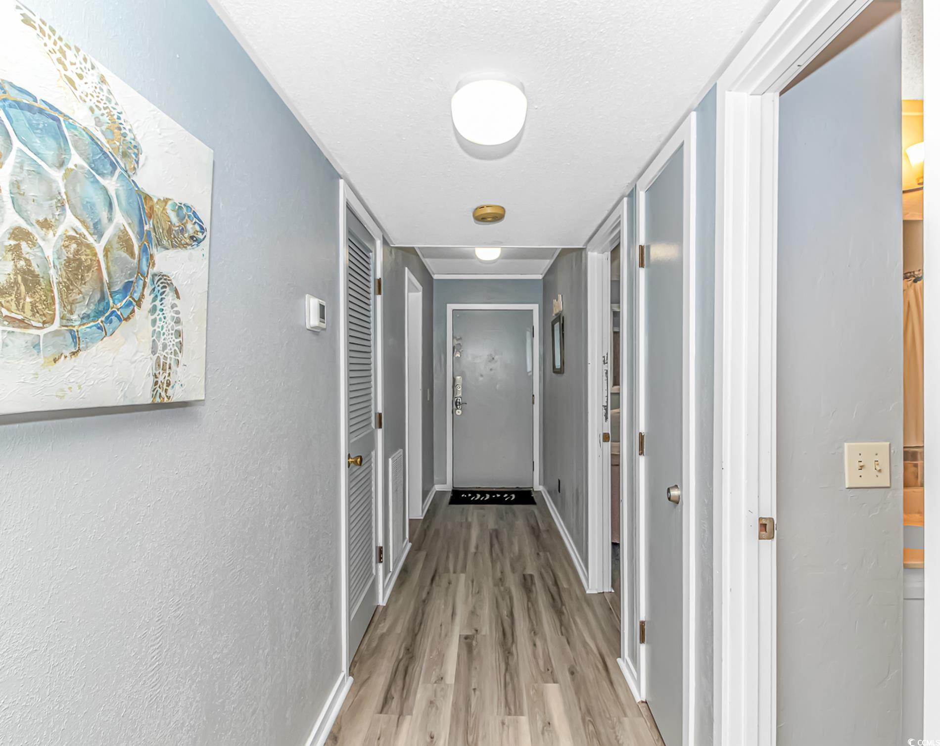 Image 3: Hallway with light wood-style floors, a textured w