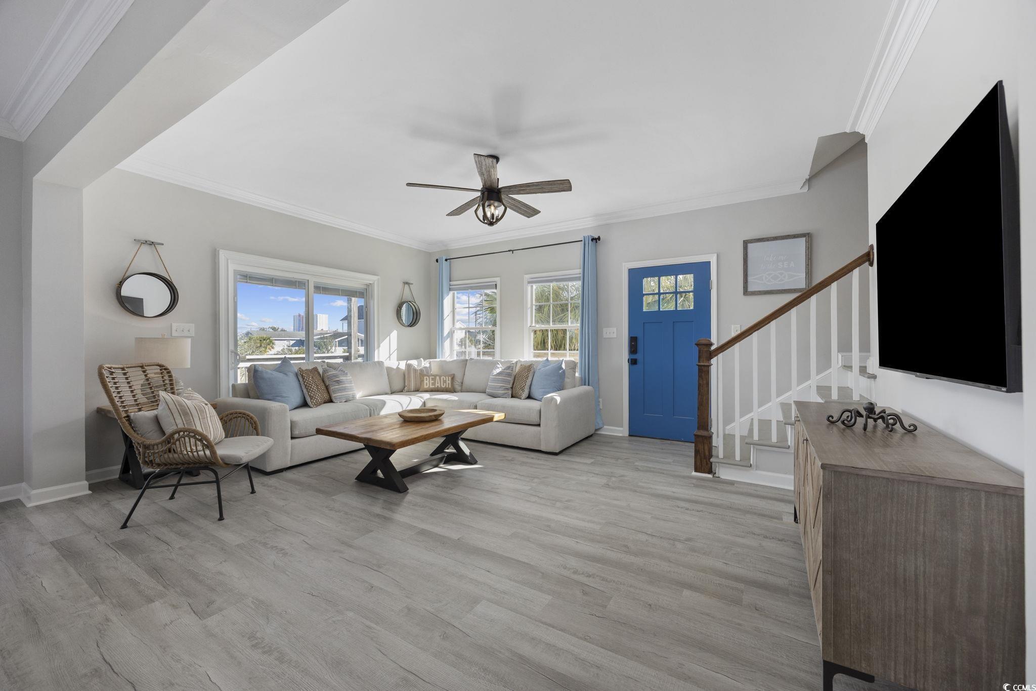 Image 4: Living room with stairway, crown molding, light wo