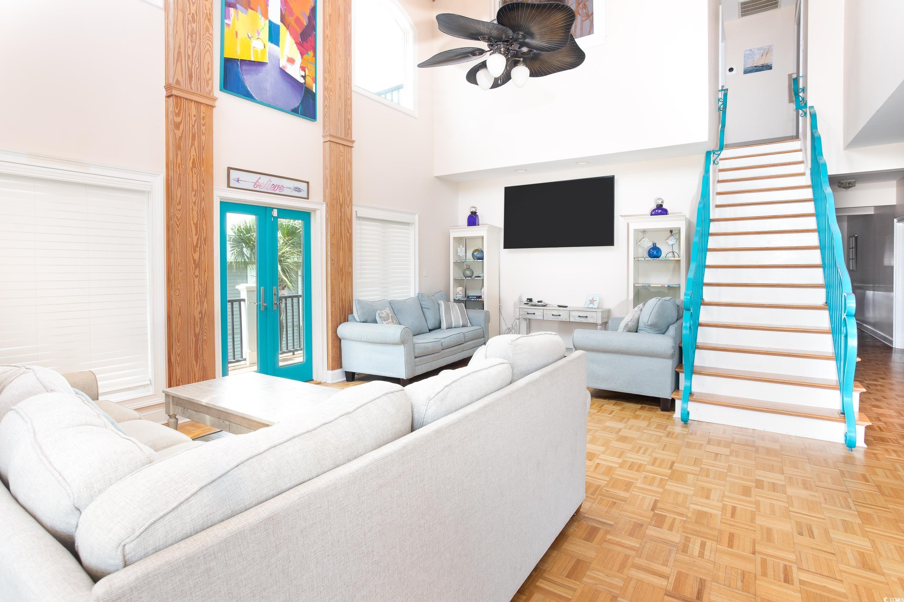 Image 4: Living room with a towering ceiling, stairs, a cei
