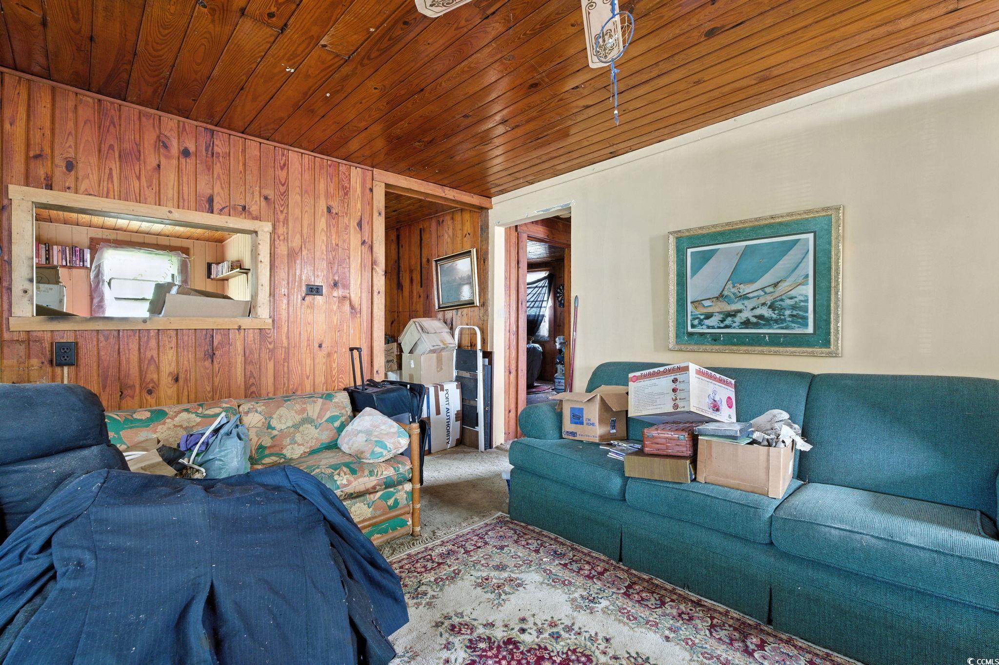 Image 3: Carpeted living area with wood walls and wood ceil