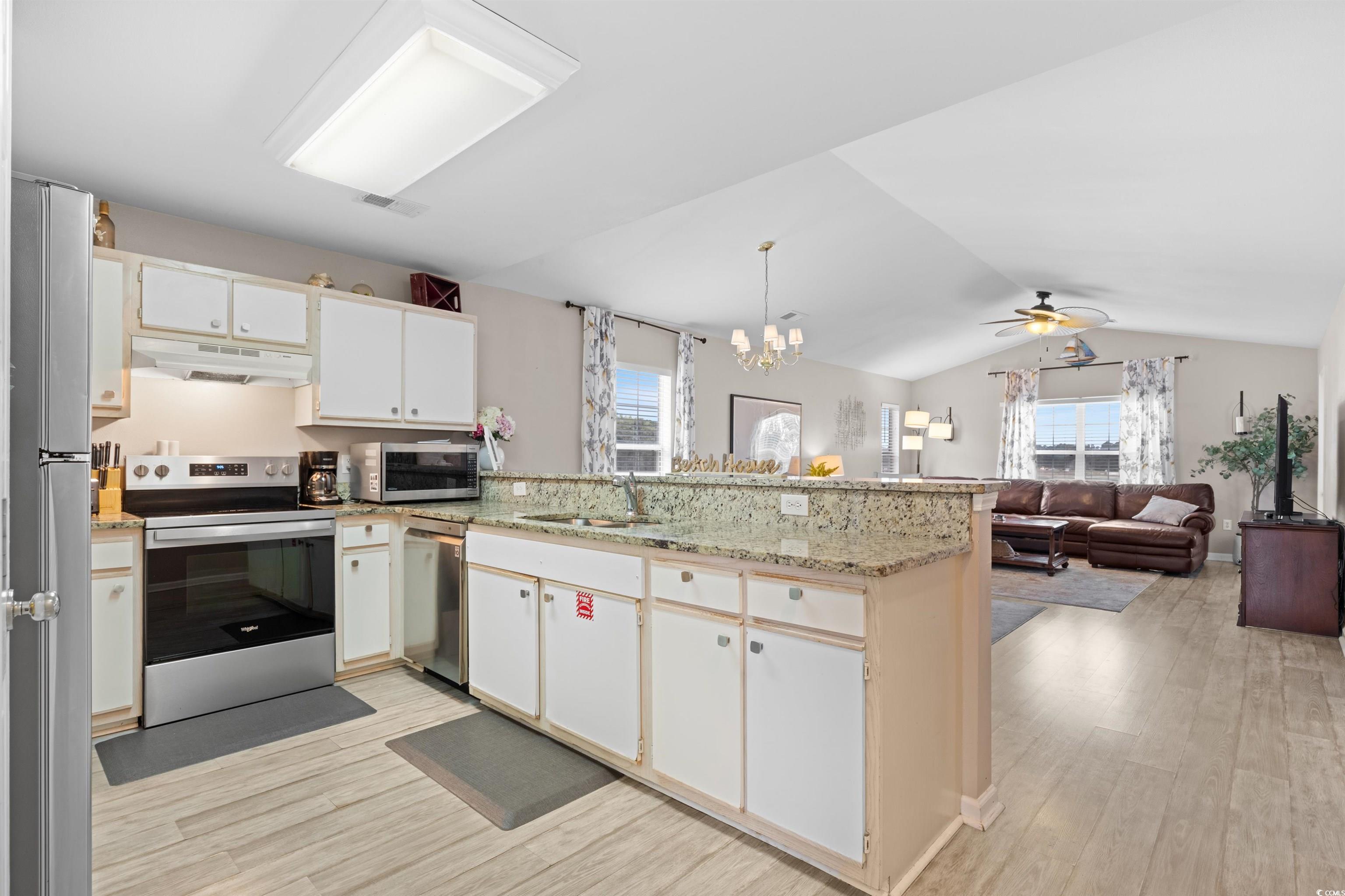 Image 4: Kitchen with a peninsula, white cabinetry, open fl