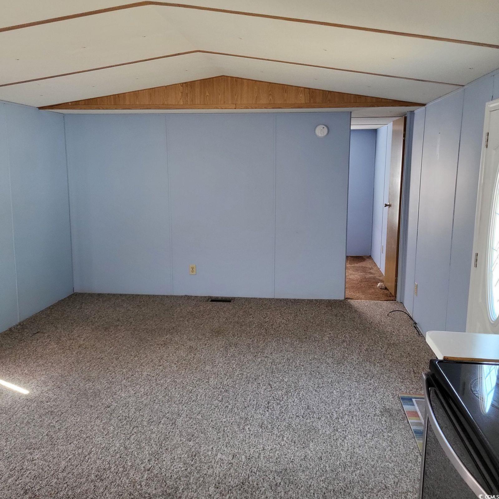 Image 2: Carpeted empty room with vaulted ceiling