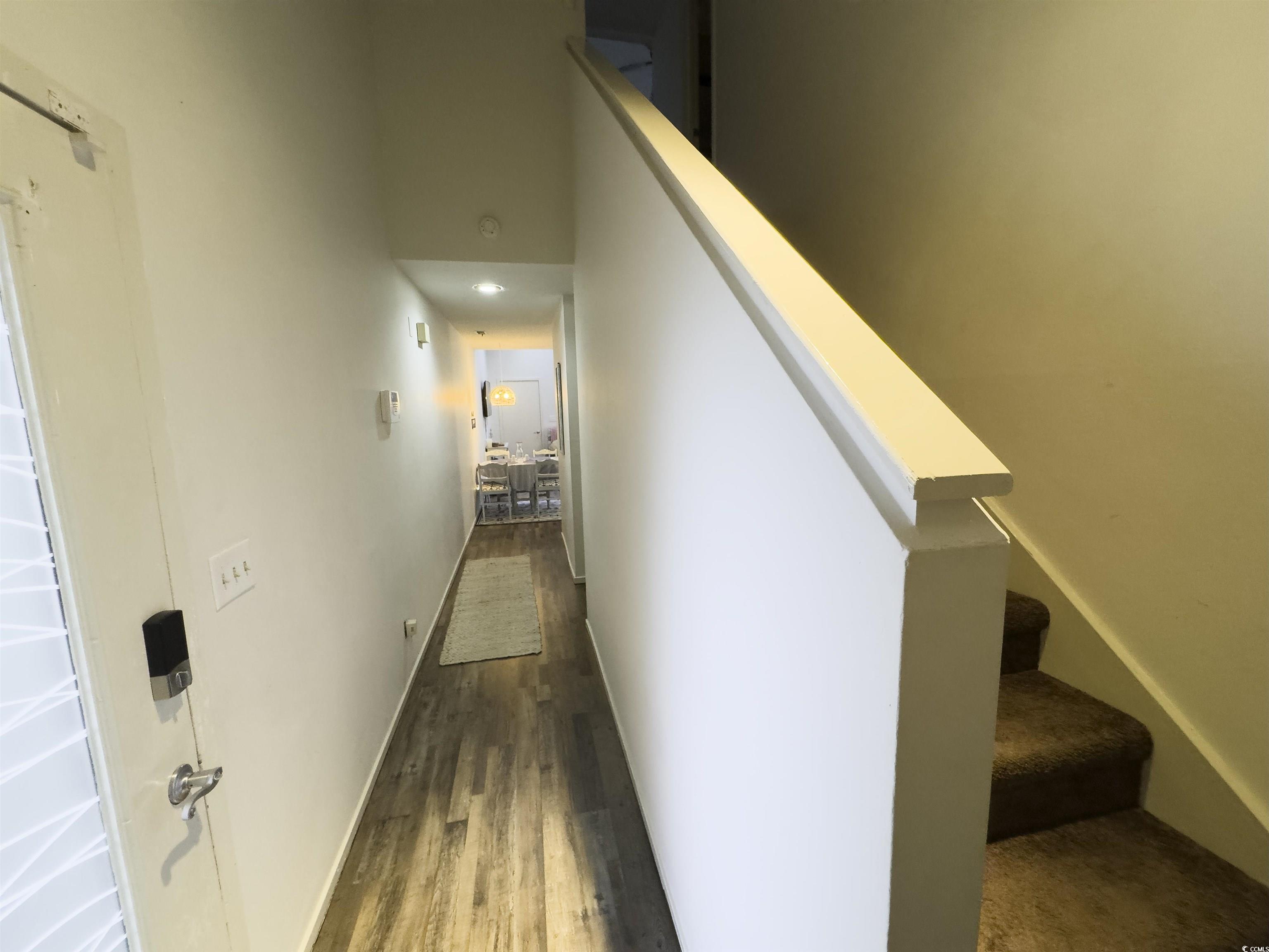 Image 3: Hall with stairs, dark wood-type flooring, and a h