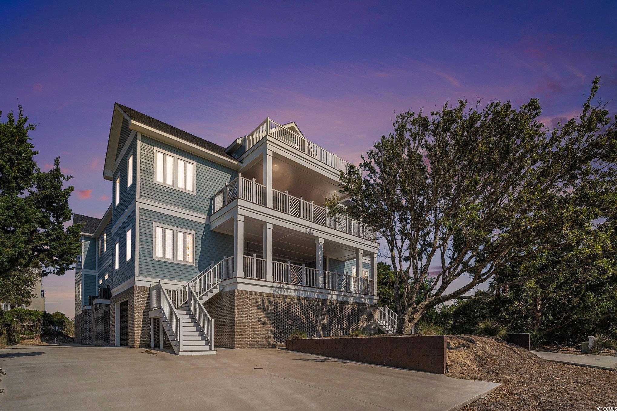 Image 1: Raised beach house with a balcony, stairs, brick s