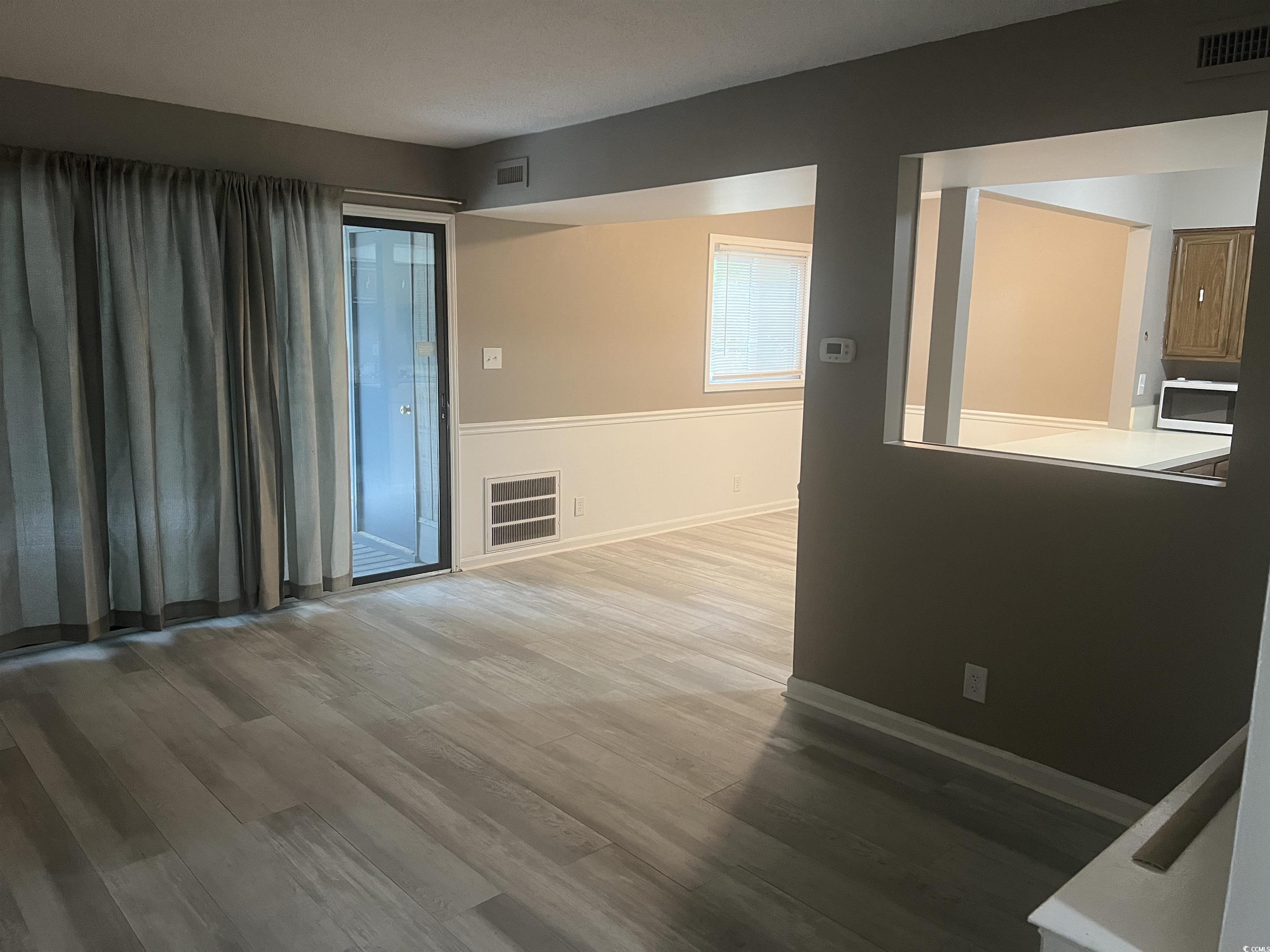 Image 4: Empty room with visible vents, wood finished floor
