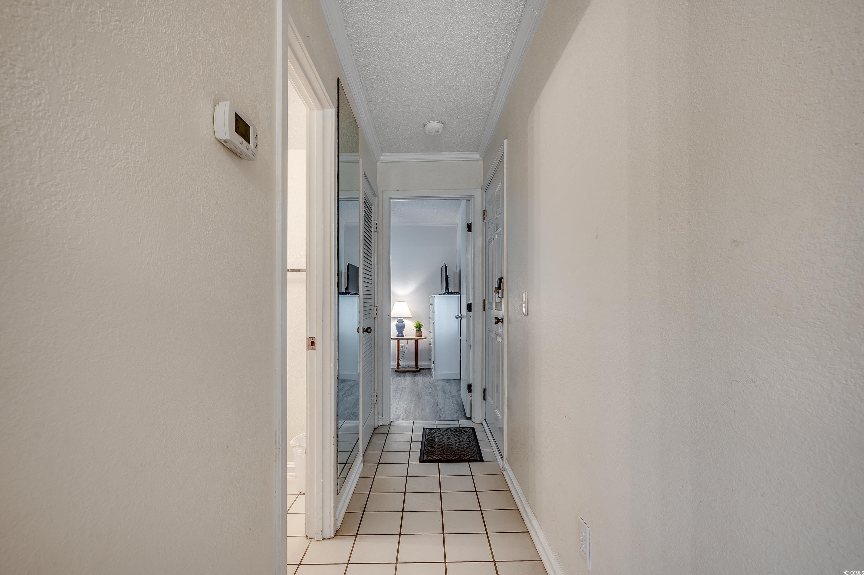 Image 2: Corridor with a textured ceiling, light tile patte