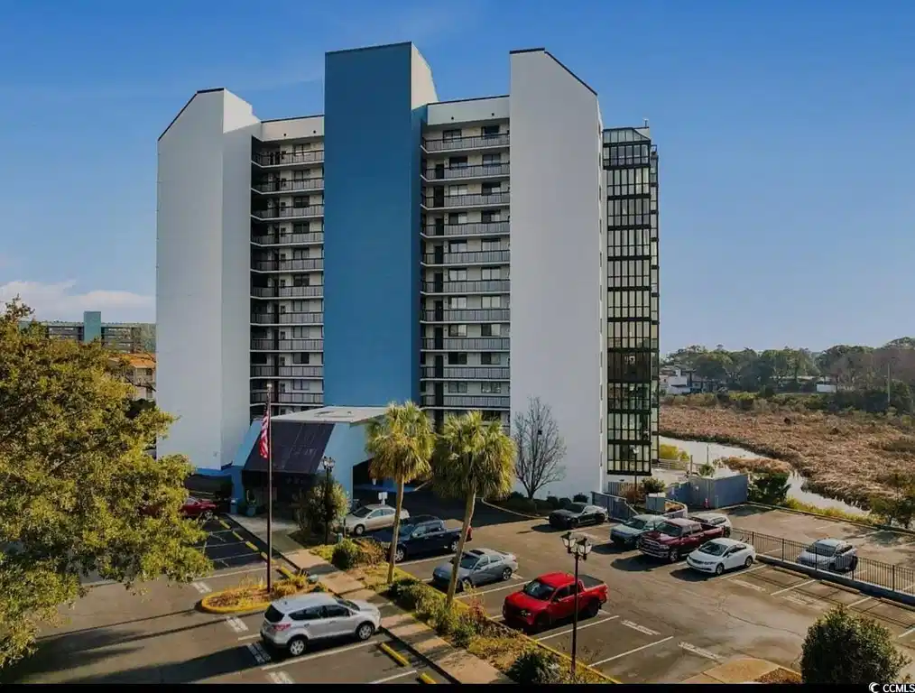 Image 1: View of building exterior featuring uncovered park