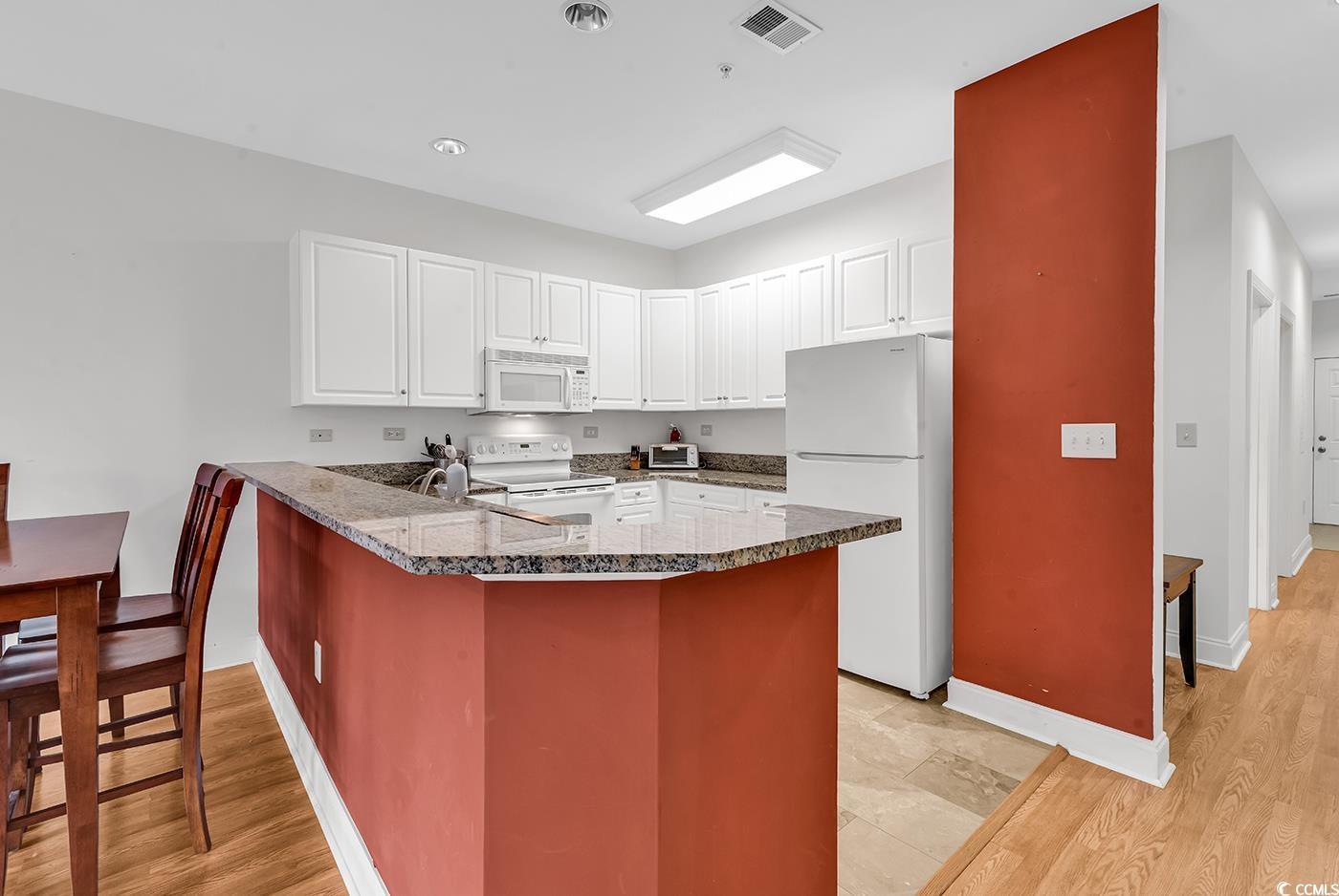Image 4: Kitchen featuring white appliances, a peninsula, w