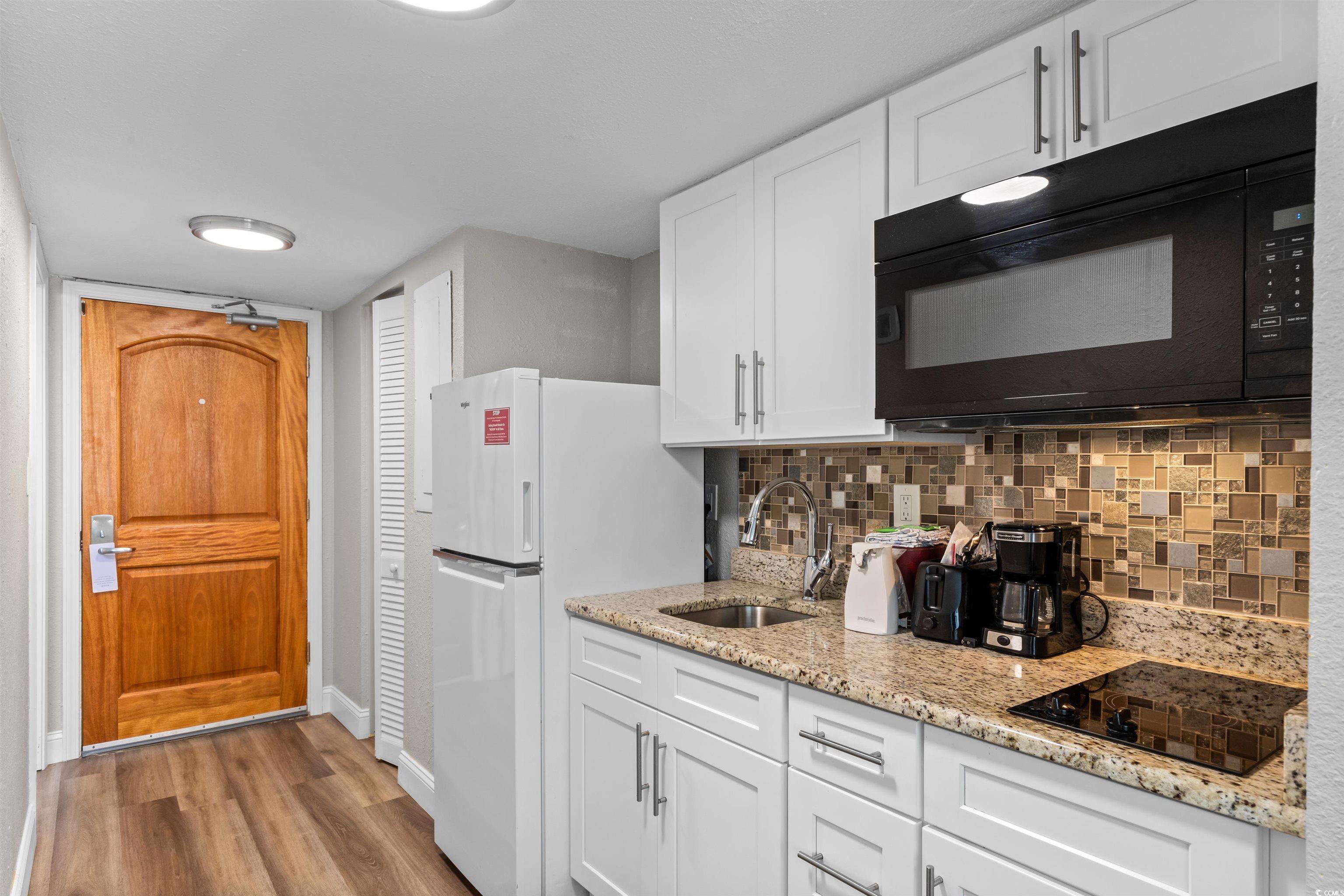 Image 2: Kitchen featuring white cabinetry, black appliance