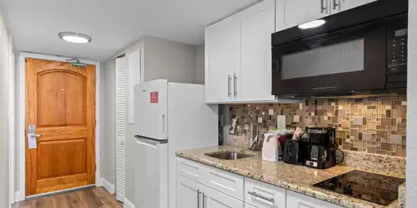 Image 2: Kitchen featuring white cabinetry, black appliance