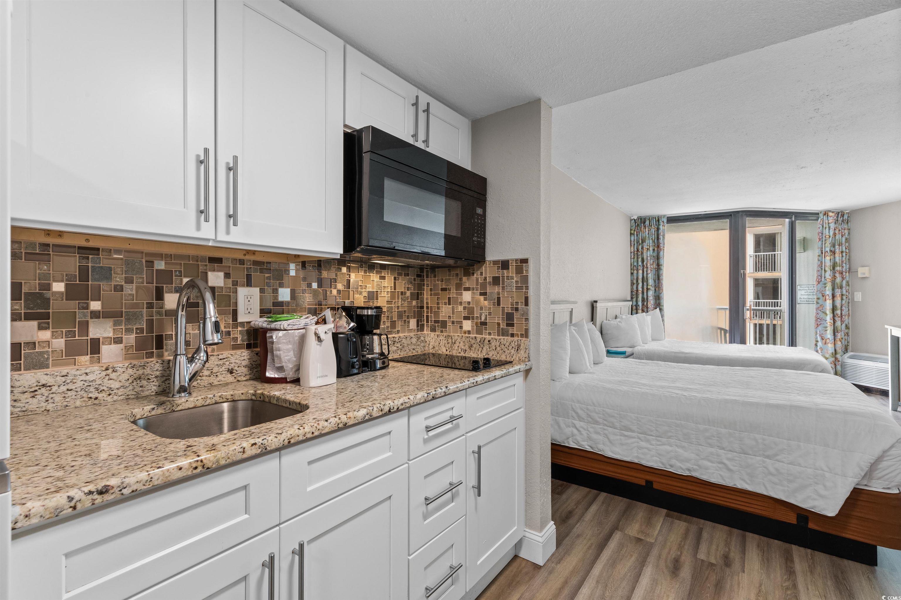 Image 3: Kitchen featuring white cabinets, light stone coun