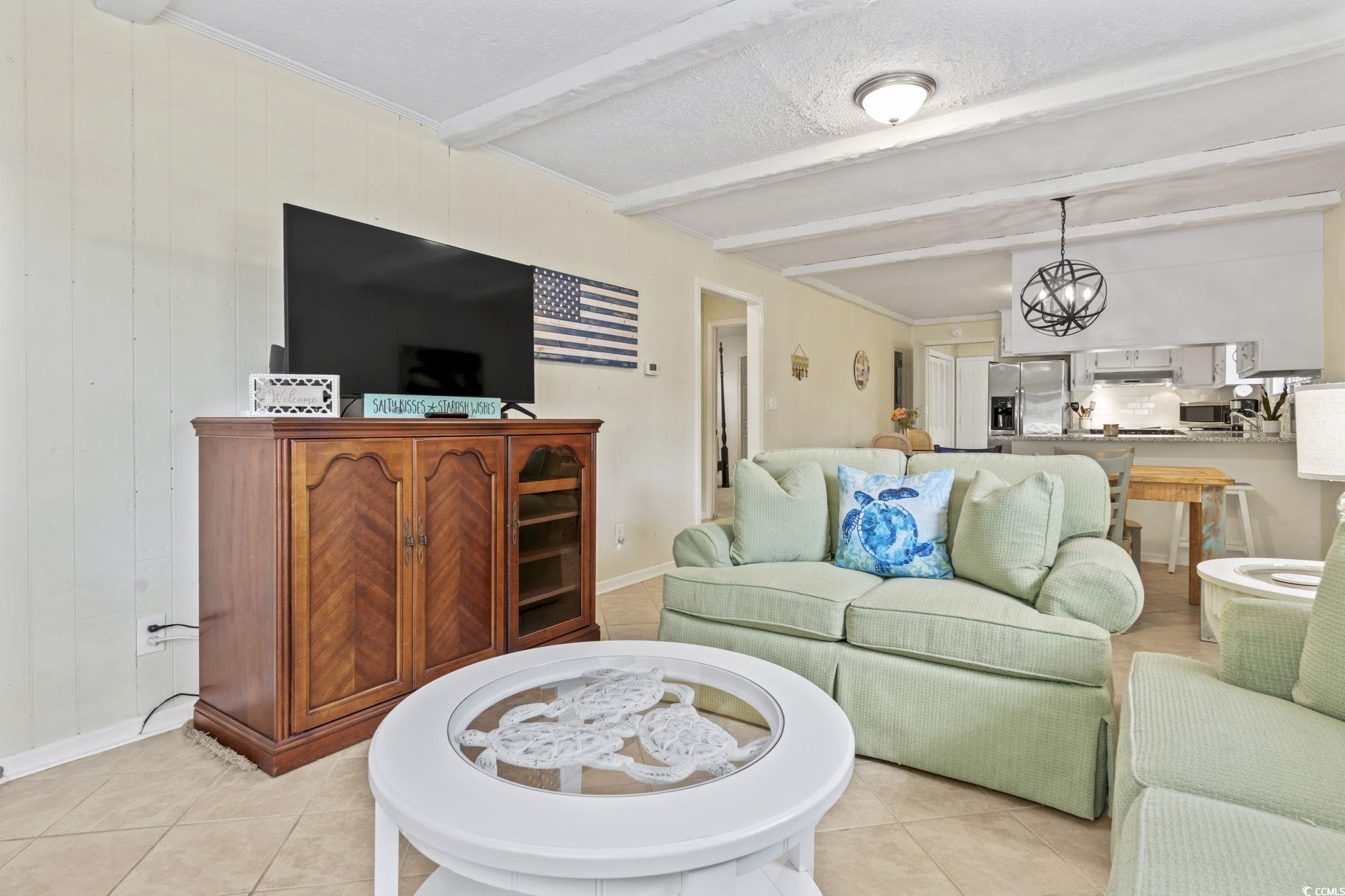 Image 4: Living room featuring beam ceiling and light tile