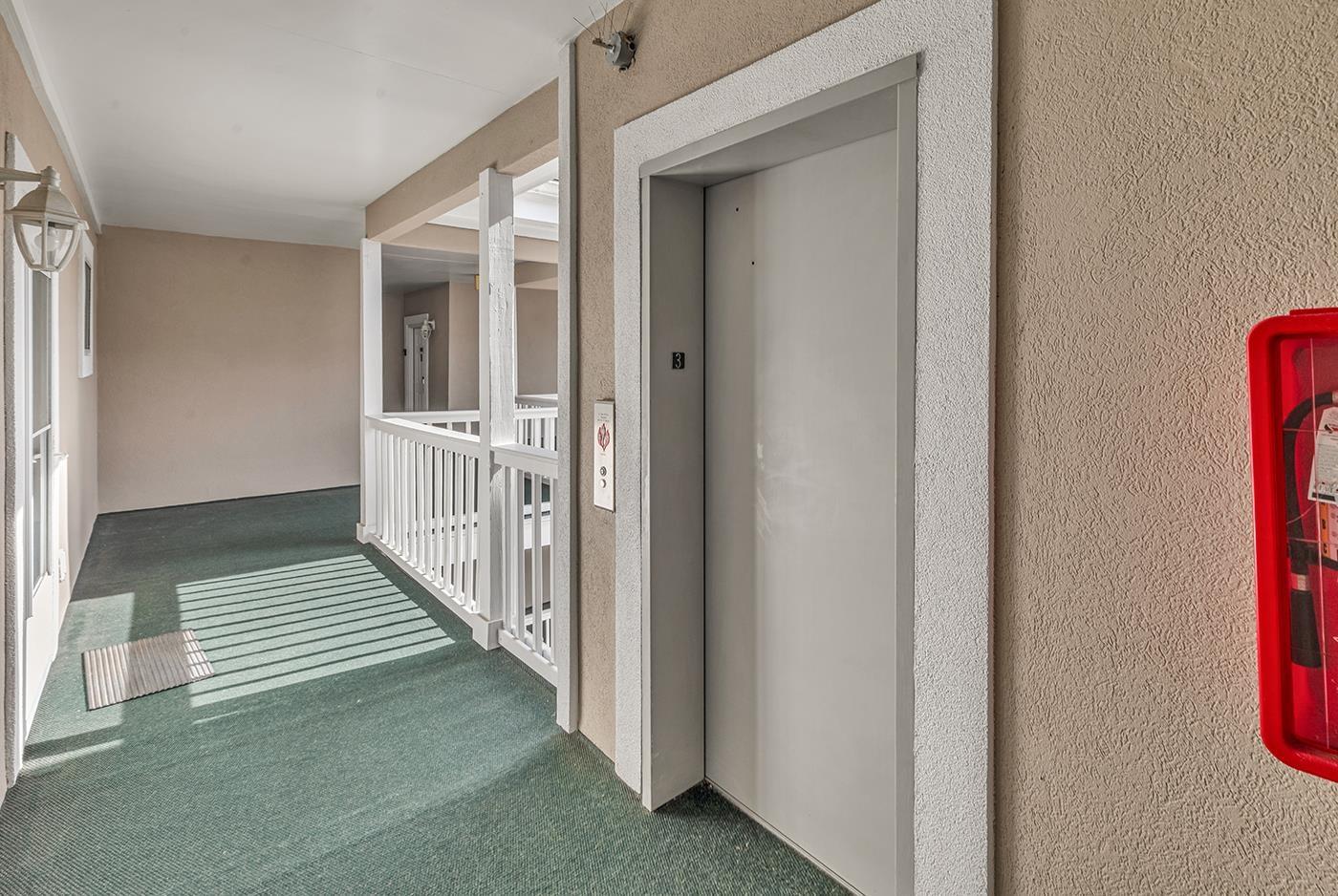 Image 3: Hallway featuring elevator, carpet, and a textured Image 3: Hallway featuring elevator, carpet, and a textured