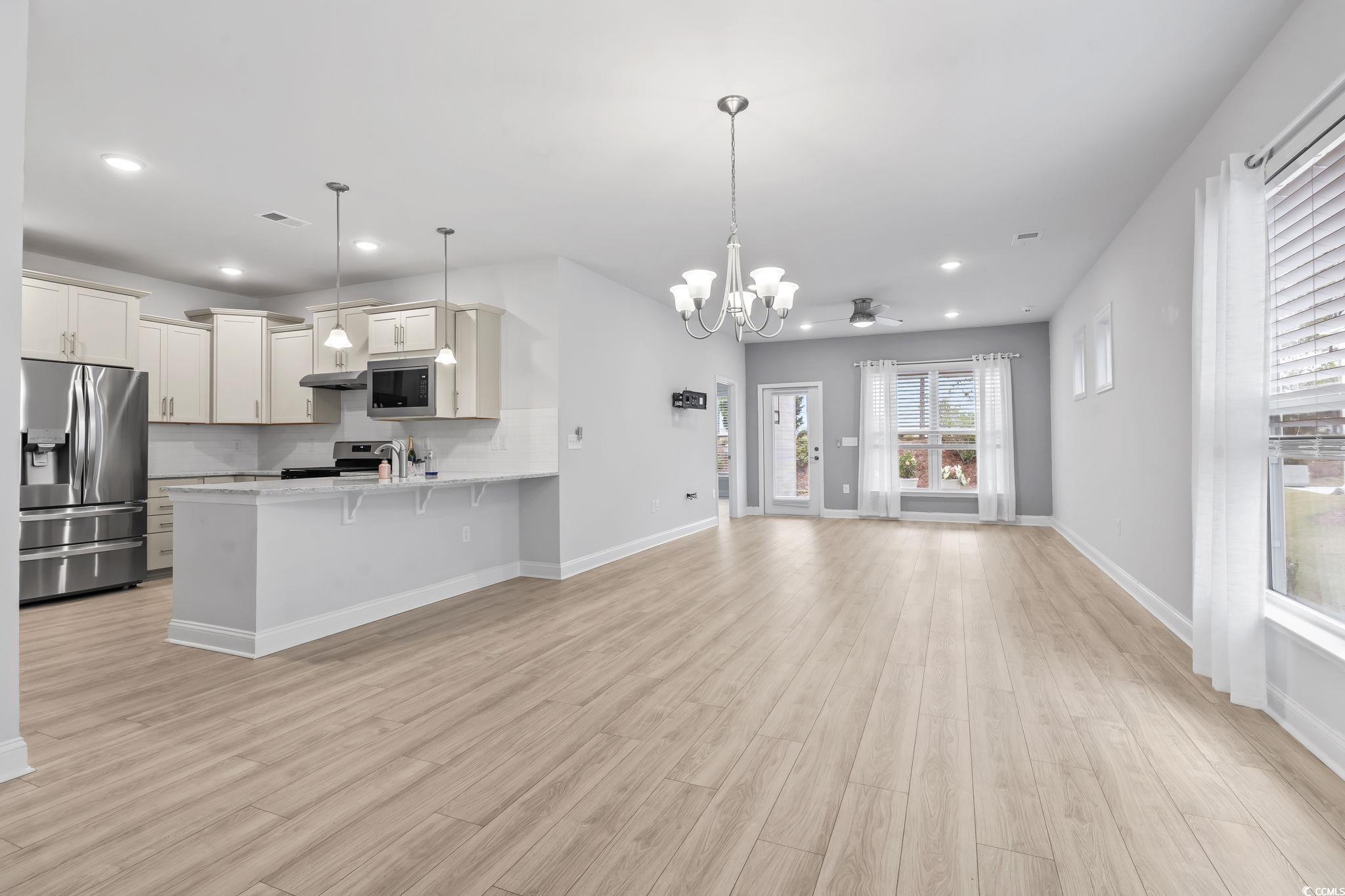 Image 2: Open floor plan, decorative light fixtures, a chan