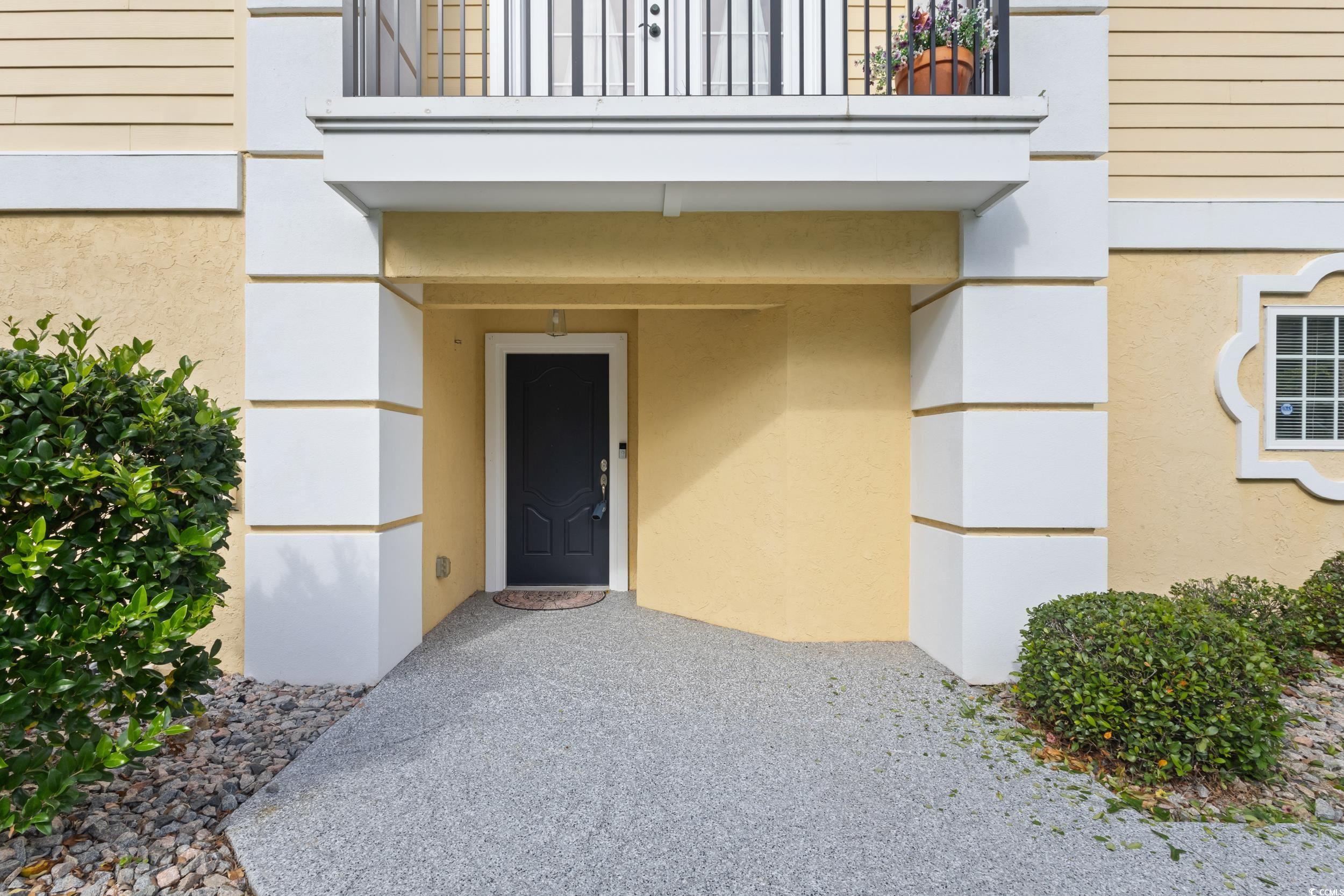 Image 2: Property entrance with a balcony and stucco siding