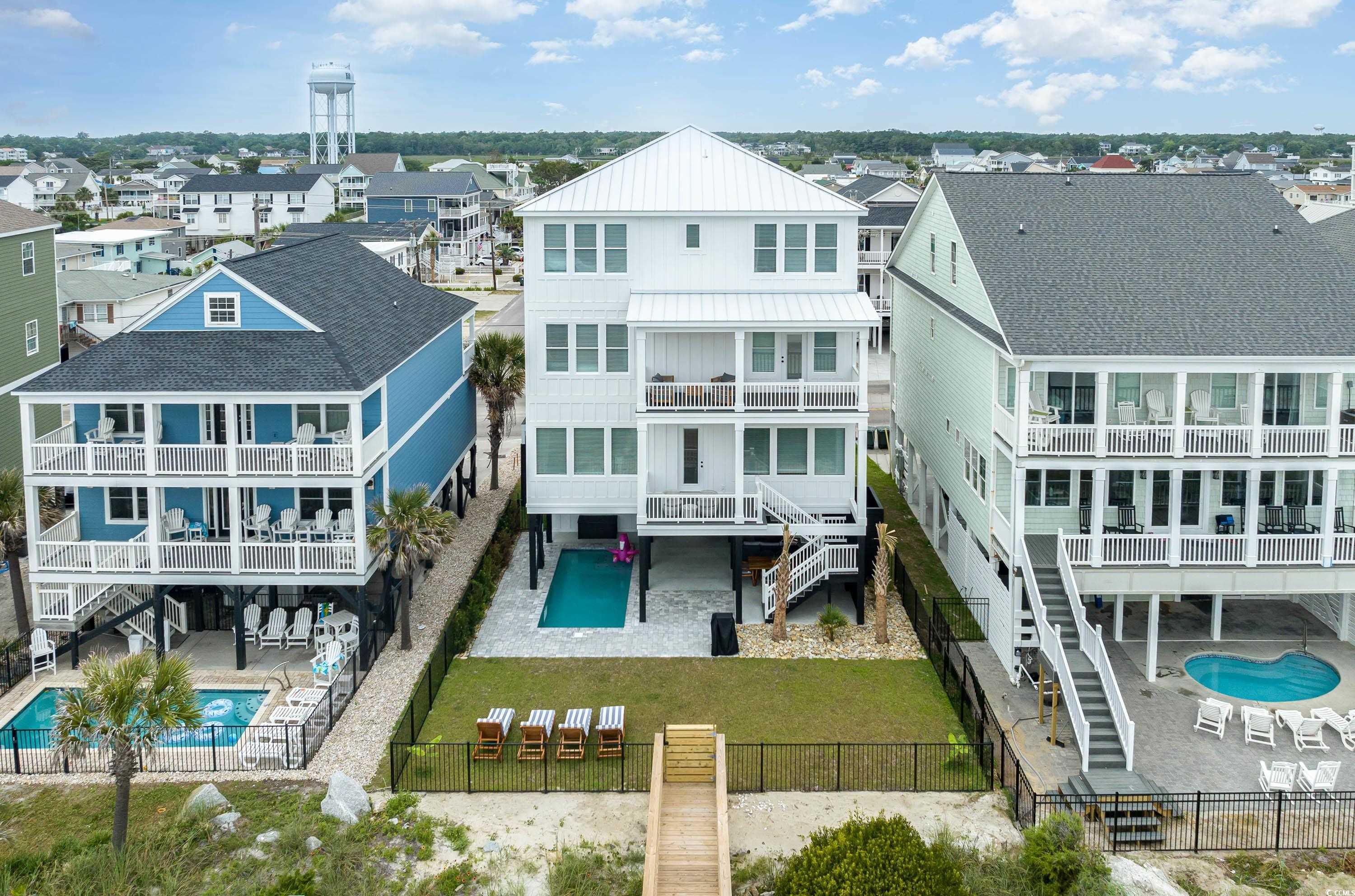 Image 3: Rear view of house with a community pool, a patio,