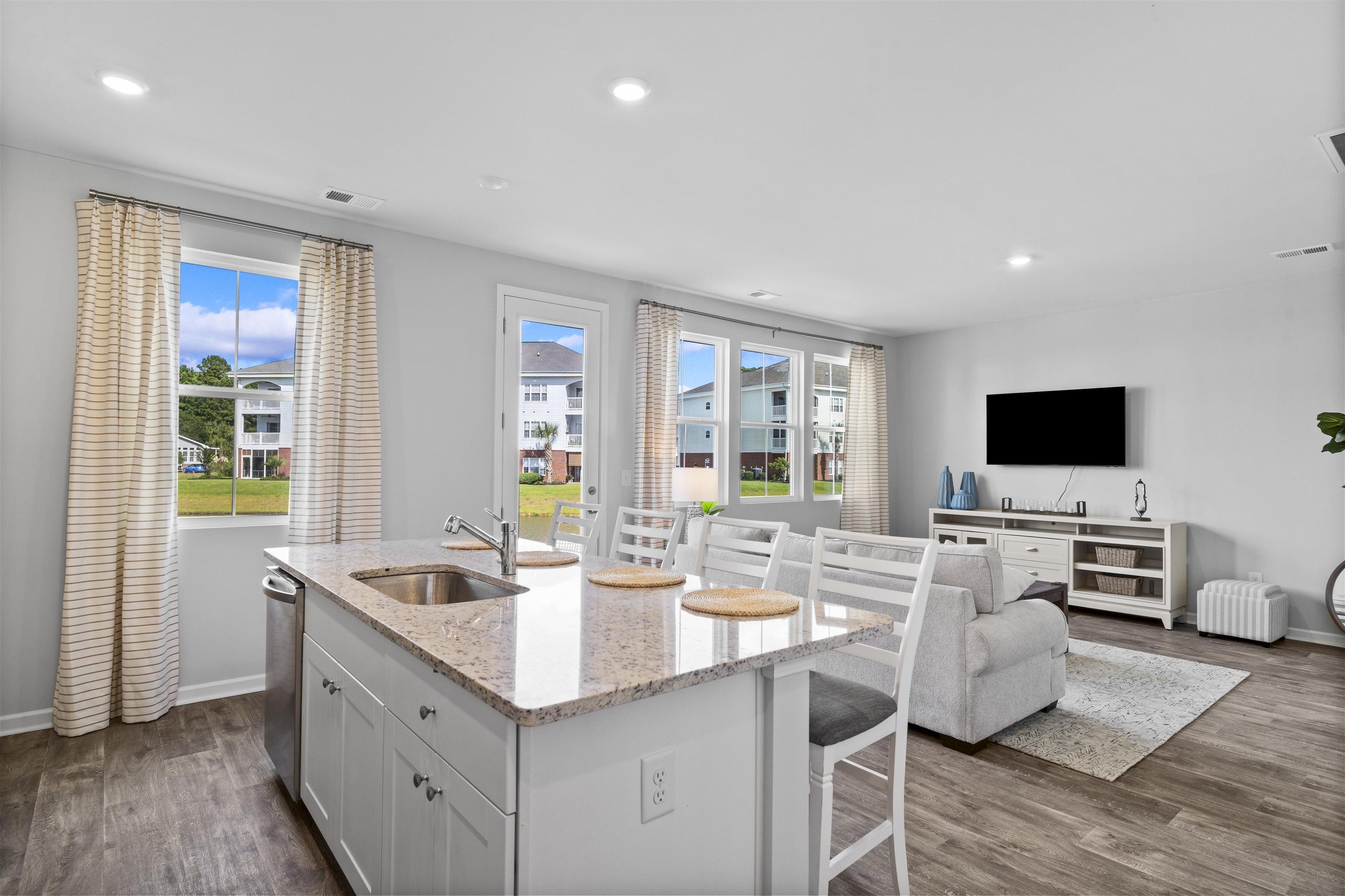 Image 4: Kitchen with light stone countertops, dark wood-st