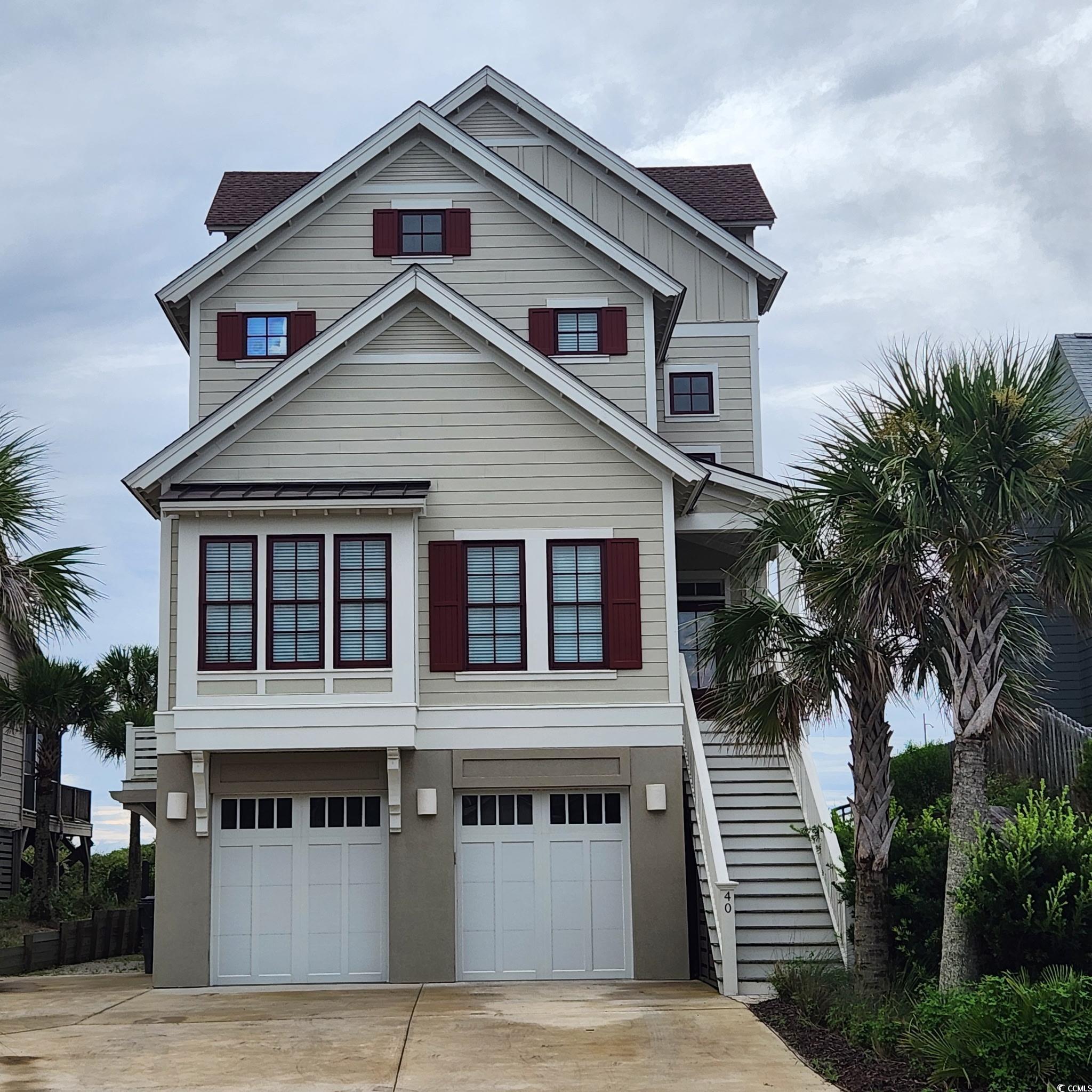 Image 2: Raised beach house with concrete driveway, stairs,