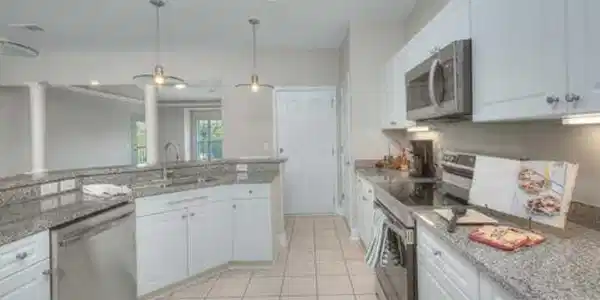 Image 4: Kitchen with white cabinetry, stainless steel appl