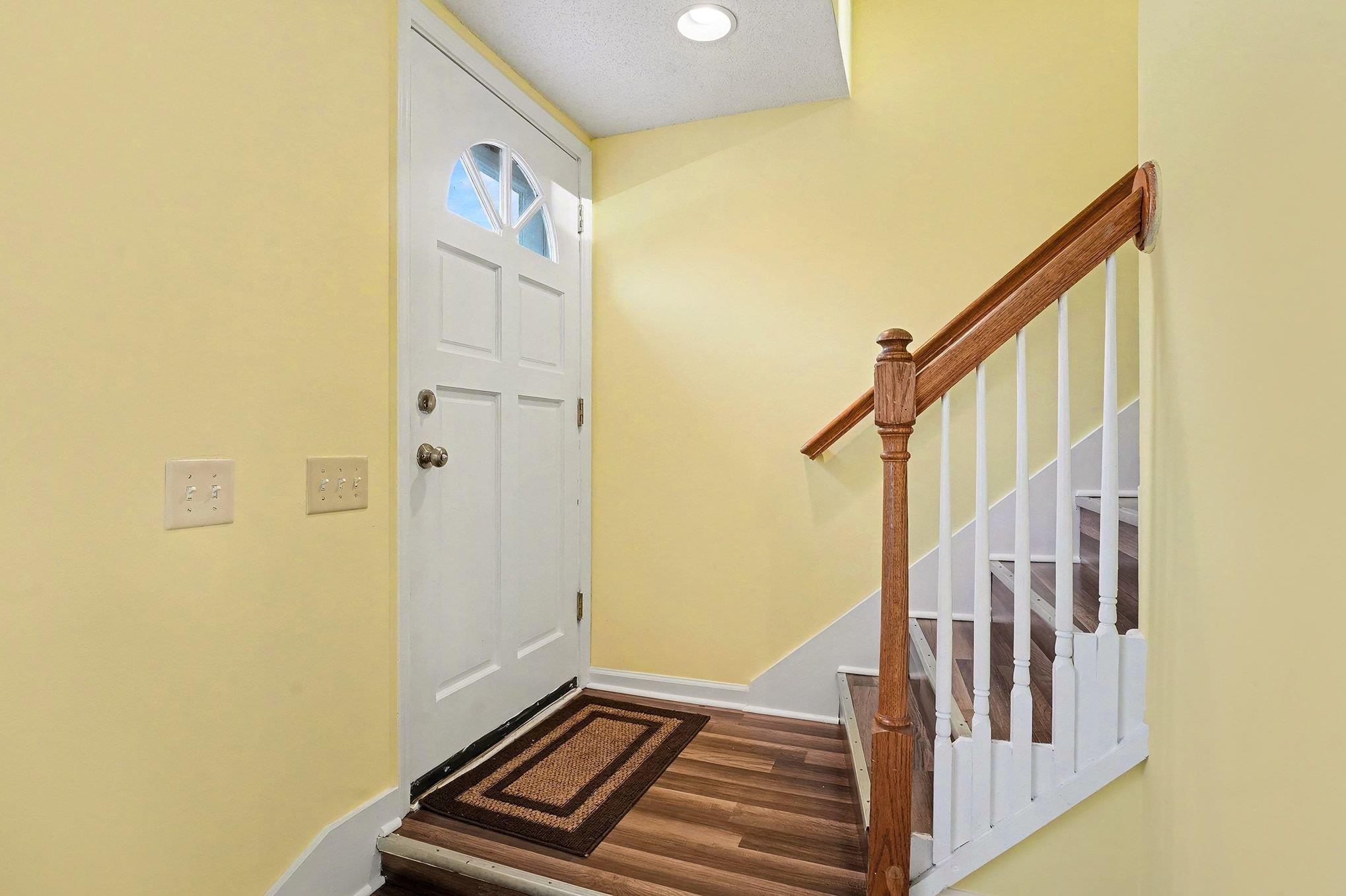 Image 4: Entryway with dark LVP floors, stairway, and reces